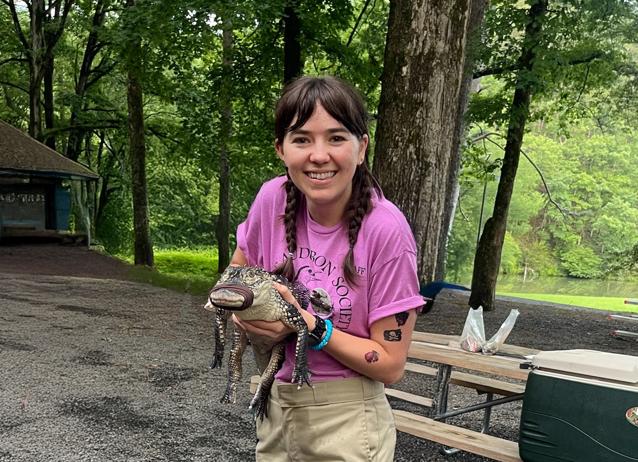 Photo of Emily Kelley holding a baby alligator with a tape mouth