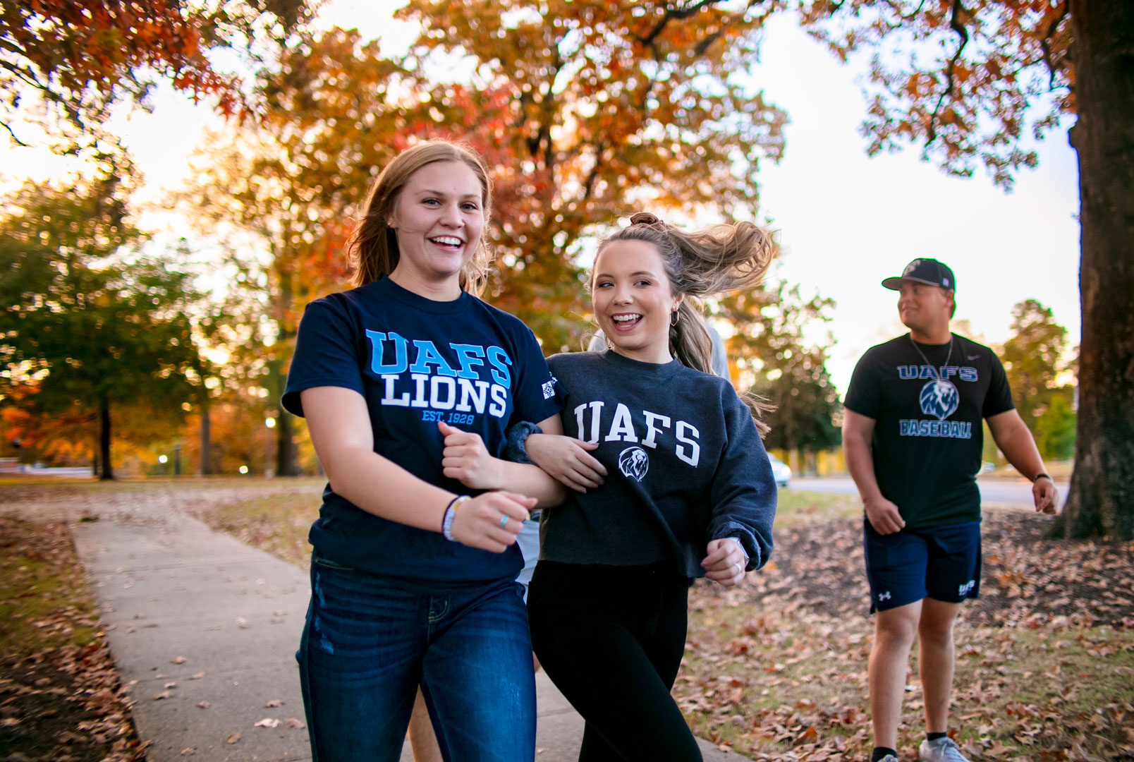 Two female students walking arm in arm