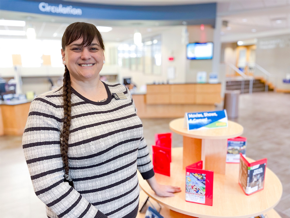 Andrea Parton, the discovery and access librarian for the Boreham Library at the University of Arkansas - Fort Smith, stands in the lobby next to a new display of video games