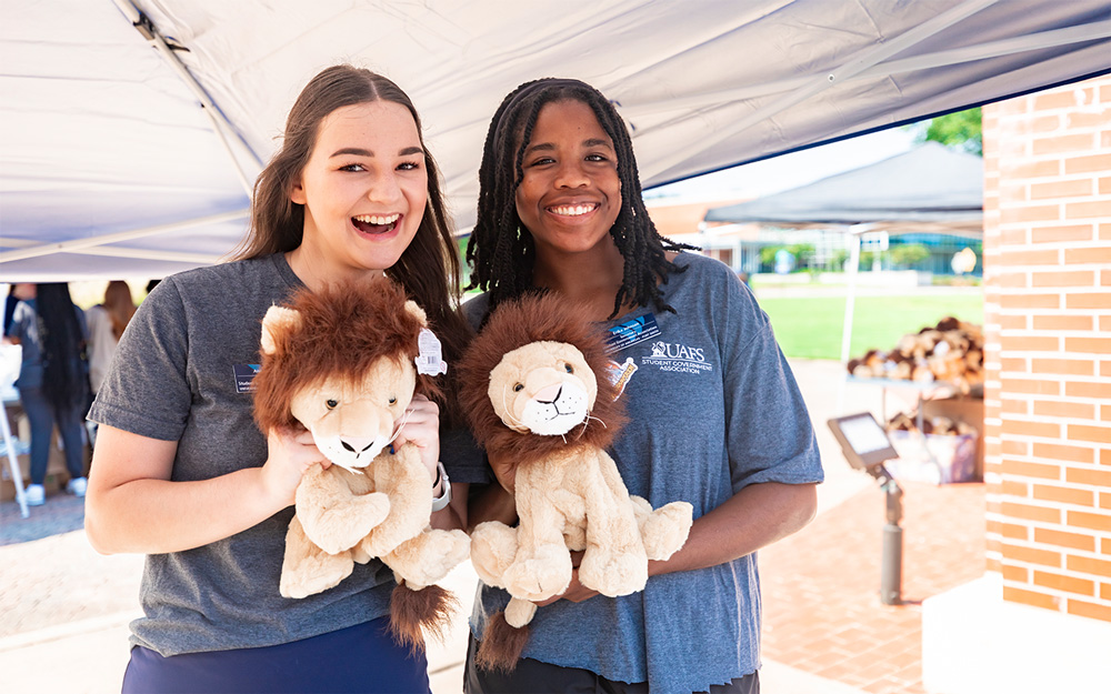 Two UAFS students each hold a stuffed Numa at the 2024 Campus Picnic and Block Party