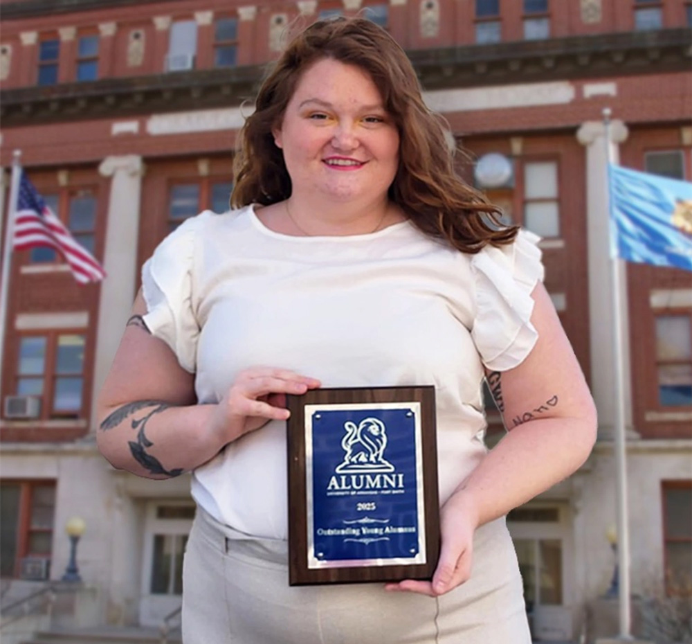 Cherokee Blanchard-Hartsell stands in front of an Oklahoma courthouse holding her UAFS Outstanding Young Alum Award