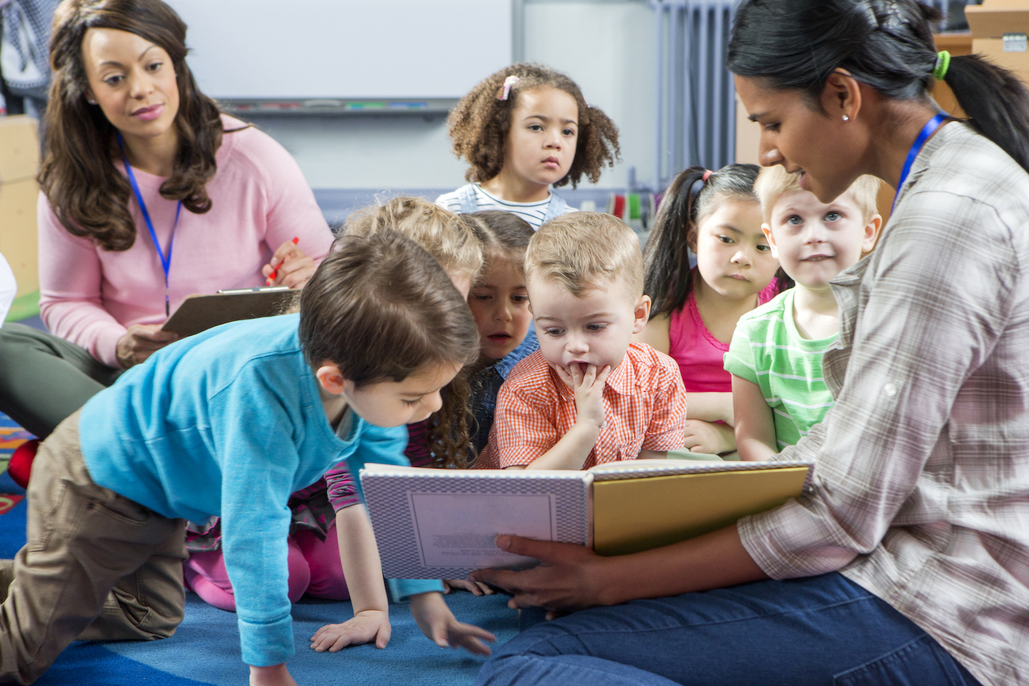 teachers and children with a book