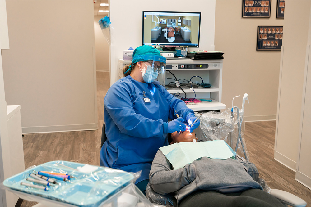 A UAFS dental hygiene student inspects the mouth of a patient