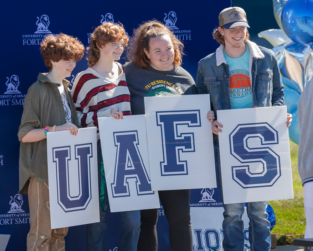 A family poses with letters that spell out UAFS at Family Weekend