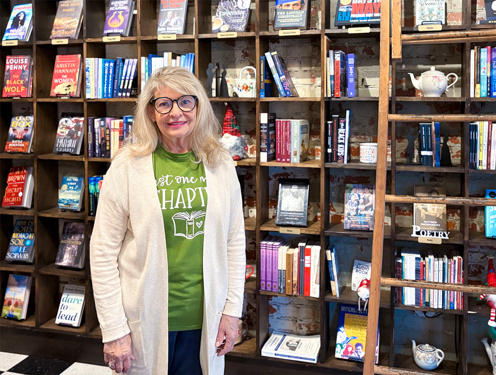 A portrait of Dr. Kristin Tardif in front of a bookcase wall at Bookish, where she is the new owner of the independent book store in downtown Fort Smith.